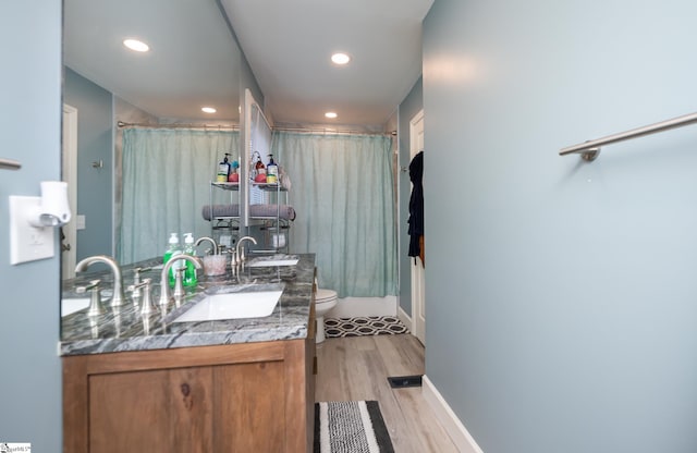 full bath featuring toilet, wood finished floors, recessed lighting, and a sink