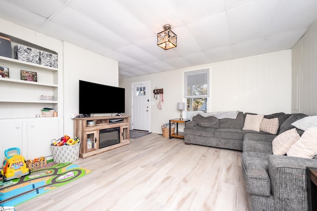 living area with a paneled ceiling and light wood-type flooring