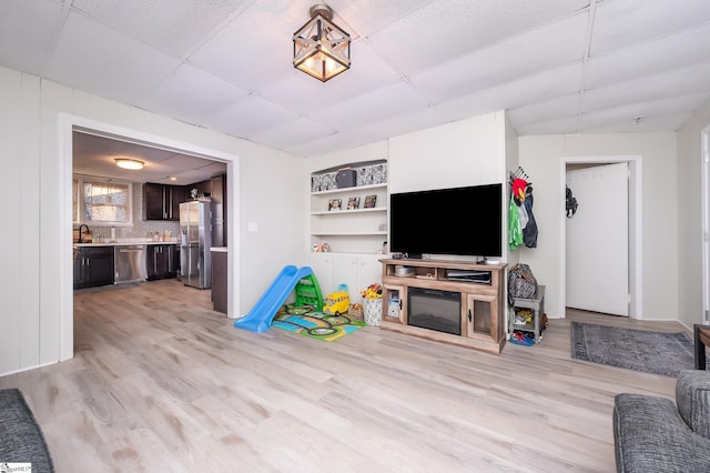 living area featuring a drop ceiling and light wood-style floors