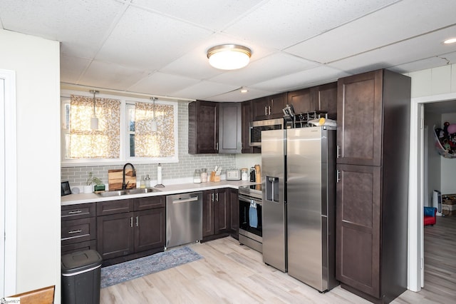 kitchen featuring a sink, appliances with stainless steel finishes, light wood finished floors, dark brown cabinets, and light countertops