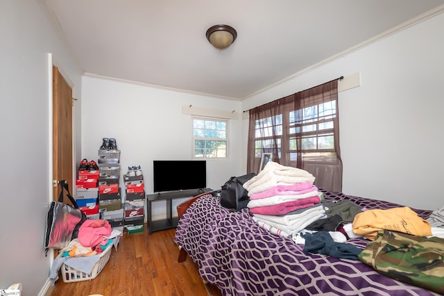 bedroom with wood finished floors and crown molding