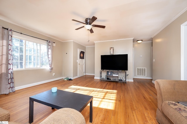 living area featuring visible vents, baseboards, wood finished floors, and crown molding