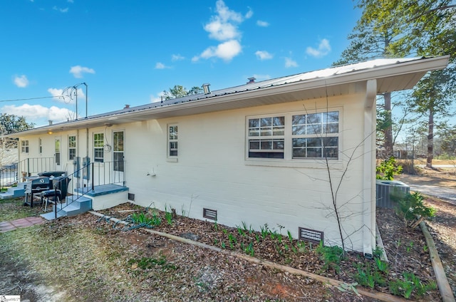 exterior space featuring central AC unit, metal roof, and crawl space