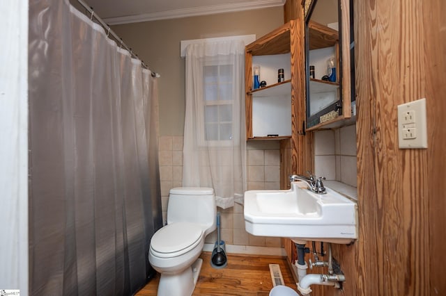 full bath featuring wood finished floors, a sink, crown molding, toilet, and tile walls