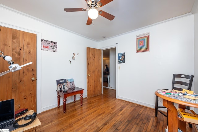 office area with baseboards, wood-type flooring, a ceiling fan, and ornamental molding