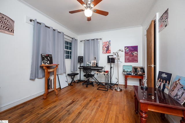 office space featuring baseboards, wood-type flooring, a ceiling fan, and crown molding