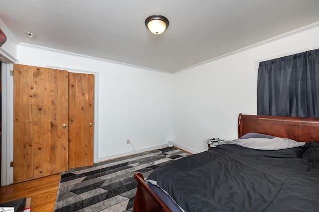 bedroom featuring crown molding, wood finished floors, and baseboards