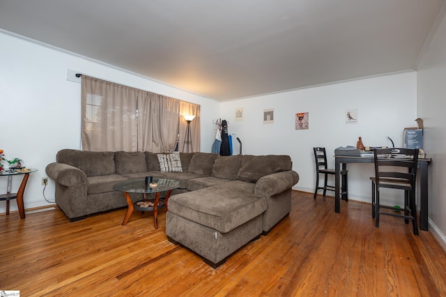 living room with light wood-type flooring, baseboards, and ornamental molding