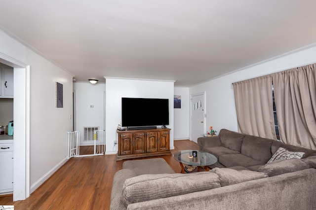 living room with visible vents, baseboards, wood finished floors, and ornamental molding