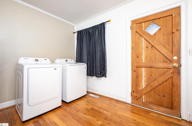 washroom featuring light wood finished floors, visible vents, washer and clothes dryer, ornamental molding, and laundry area