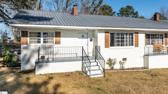 view of front facade featuring crawl space, a front lawn, metal roof, and a chimney