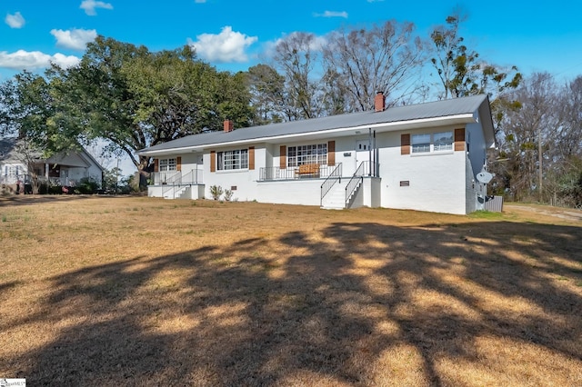 view of front of property featuring a porch, metal roof, a front yard, crawl space, and a chimney