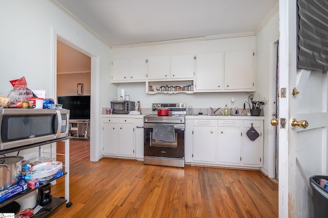 kitchen featuring light wood finished floors, white cabinets, stainless steel appliances, and ornamental molding