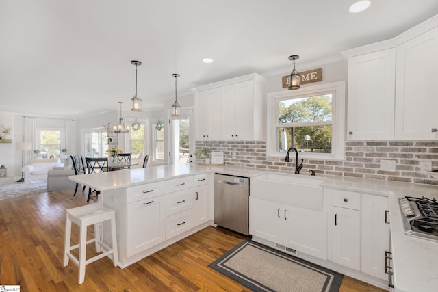 kitchen featuring a peninsula, a sink, stainless steel appliances, light countertops, and open floor plan