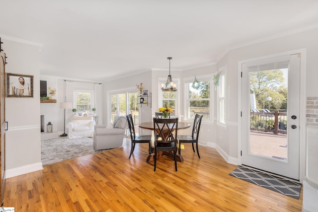 dining area featuring light wood finished floors, a chandelier, and crown molding