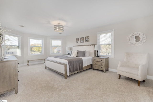 bedroom featuring light colored carpet, baseboards, and multiple windows