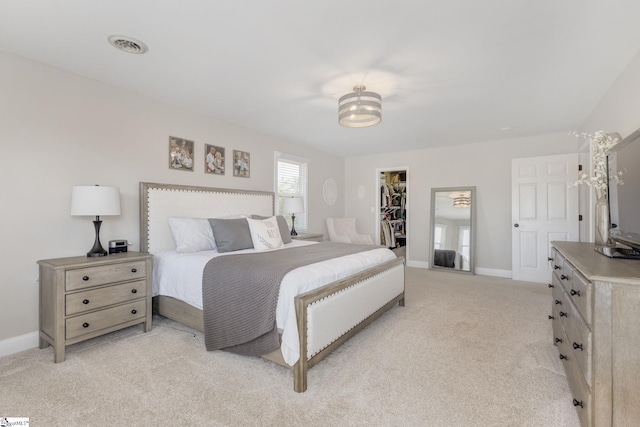 bedroom featuring visible vents, baseboards, a closet, light carpet, and a walk in closet