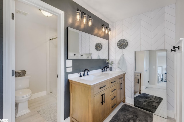 bathroom featuring a sink, toilet, a shower stall, and double vanity