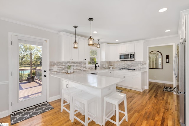 kitchen featuring white cabinetry, a peninsula, tasteful backsplash, and stainless steel appliances