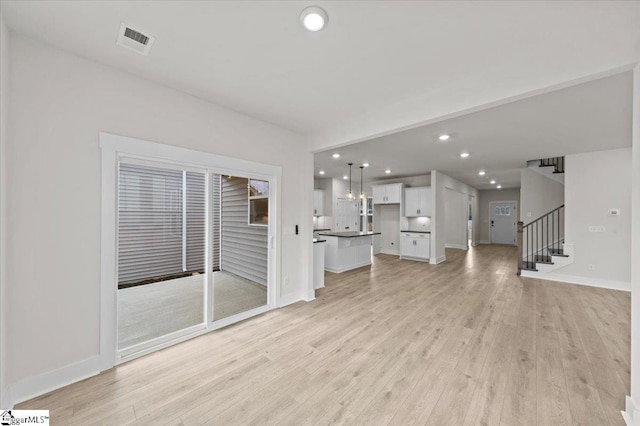 unfurnished living room featuring stairs, recessed lighting, visible vents, and light wood-type flooring