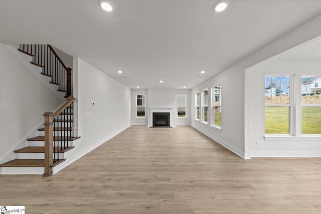 unfurnished living room with a fireplace with flush hearth, recessed lighting, and light wood-style floors