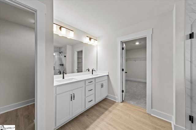 full bathroom with double vanity, a stall shower, a walk in closet, and a sink