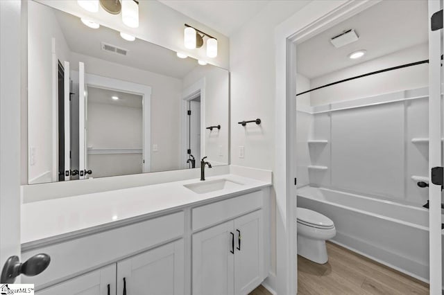 bathroom featuring visible vents, toilet, wood finished floors, shower / bathing tub combination, and vanity