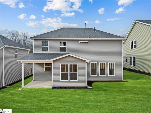 rear view of property featuring a yard, a shingled roof, and a patio