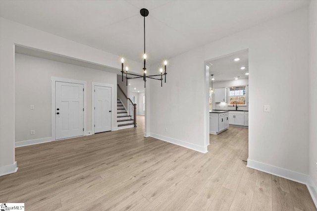 unfurnished dining area with stairs, light wood-style floors, baseboards, and a sink