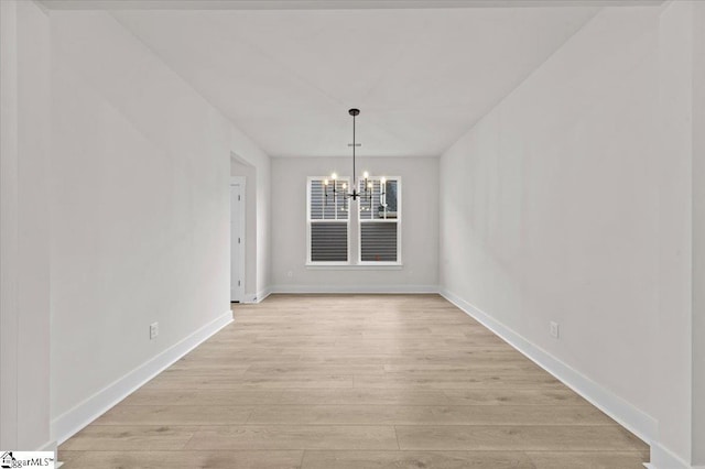 unfurnished dining area featuring baseboards, light wood-type flooring, and a chandelier