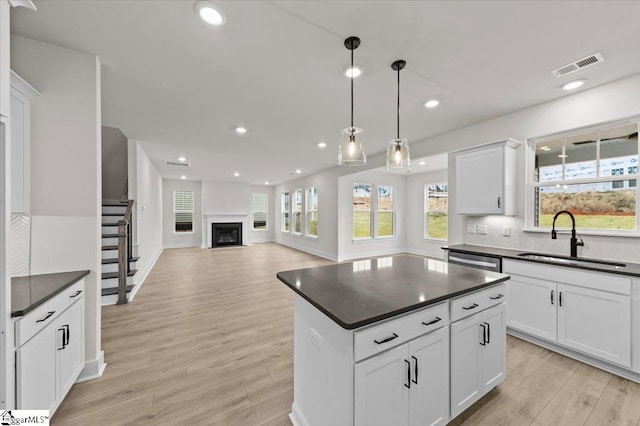 kitchen featuring a sink, visible vents, dark countertops, and backsplash