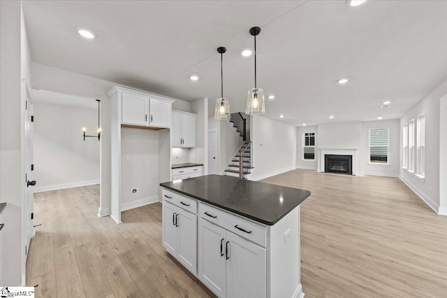 kitchen with dark countertops, white cabinetry, recessed lighting, a fireplace, and light wood finished floors