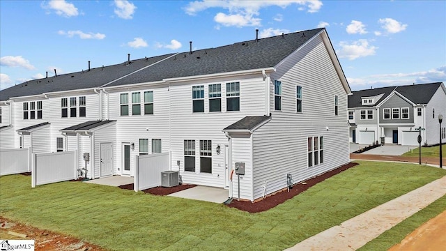 rear view of house featuring fence, a lawn, central AC unit, and a patio area