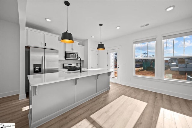 kitchen with visible vents, a sink, light countertops, appliances with stainless steel finishes, and backsplash