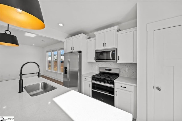 kitchen with a sink, light countertops, white cabinets, appliances with stainless steel finishes, and backsplash