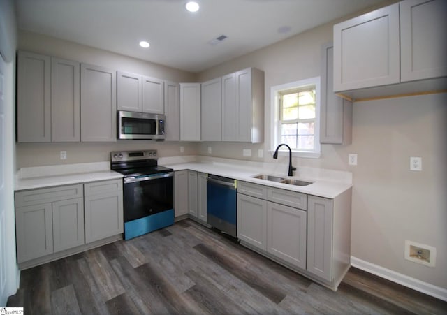 kitchen featuring a sink, dark wood-type flooring, appliances with stainless steel finishes, and gray cabinets