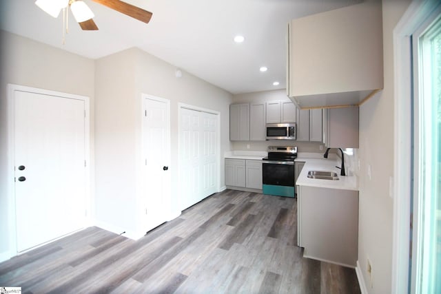 kitchen featuring light wood-style flooring, gray cabinets, a sink, stainless steel appliances, and light countertops