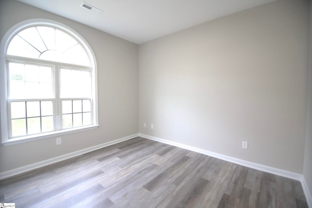 empty room featuring visible vents, baseboards, and wood finished floors