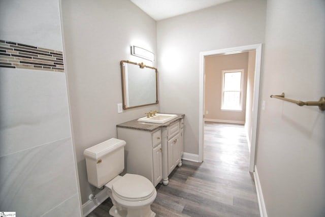 bathroom featuring toilet, vanity, baseboards, and wood finished floors