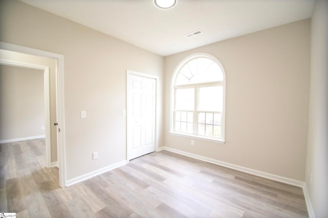 unfurnished bedroom featuring light wood finished floors, visible vents, a closet, and baseboards