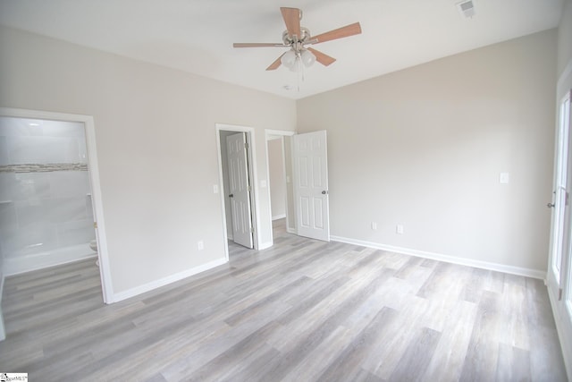 unfurnished bedroom with ceiling fan, baseboards, a walk in closet, and light wood-style floors