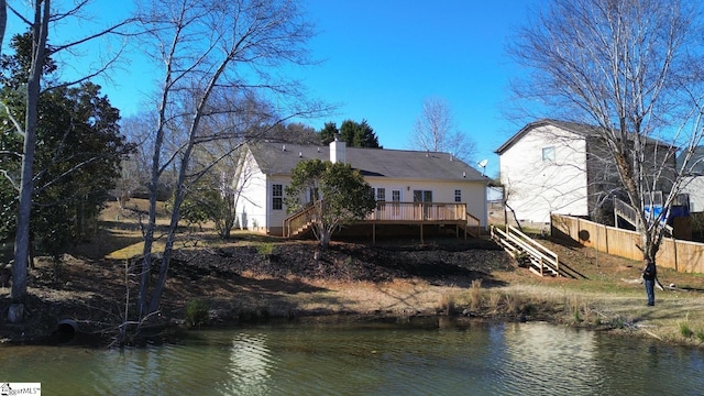 back of property featuring stairs, a deck with water view, fence, and a chimney