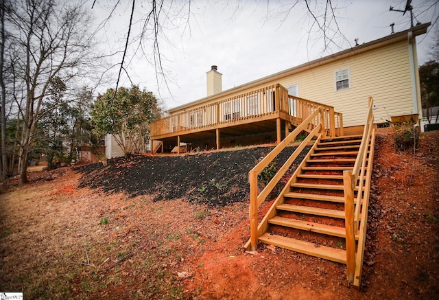 back of property featuring stairs, a wooden deck, and a chimney