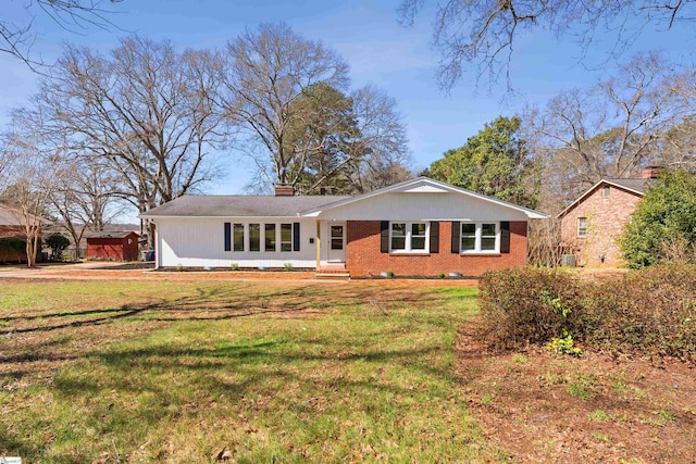 ranch-style house featuring brick siding, a chimney, and a front yard