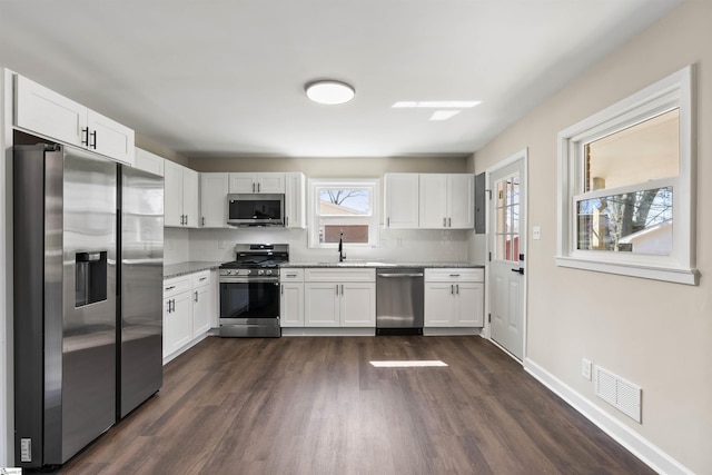 kitchen featuring visible vents, a sink, dark wood-style floors, stainless steel appliances, and white cabinets