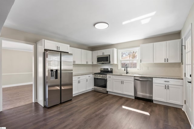 kitchen with a sink, dark wood-type flooring, appliances with stainless steel finishes, and white cabinetry