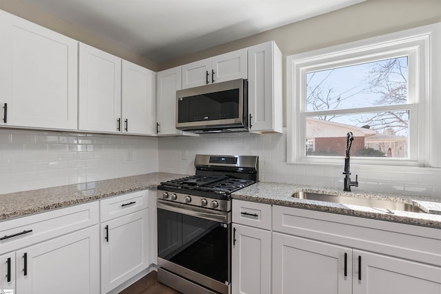 kitchen with appliances with stainless steel finishes, white cabinetry, and a sink