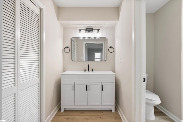 bathroom with toilet, baseboards, and wood finished floors