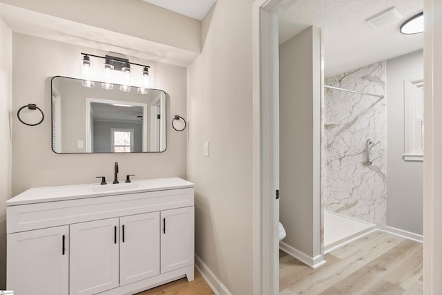 full bath featuring vanity, toilet, wood finished floors, and a marble finish shower