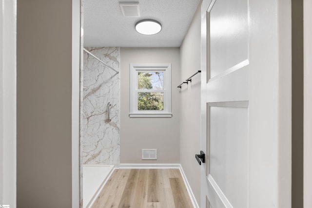 laundry area with visible vents, baseboards, a textured ceiling, and wood finished floors